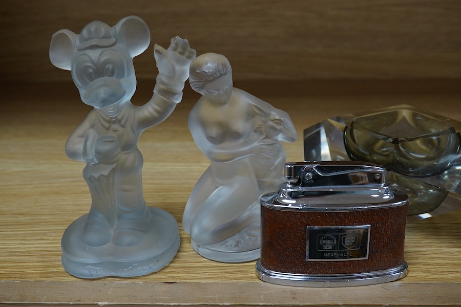 Two Lalique glass figures; a kneeling woman and deer group, a budgerigar, together with a Ronson ‘Senator’ Shell BP desk lighter, a Murano glass ash tray, an Art Deco style glass ram, etc. (7). Condition - poor to fair.